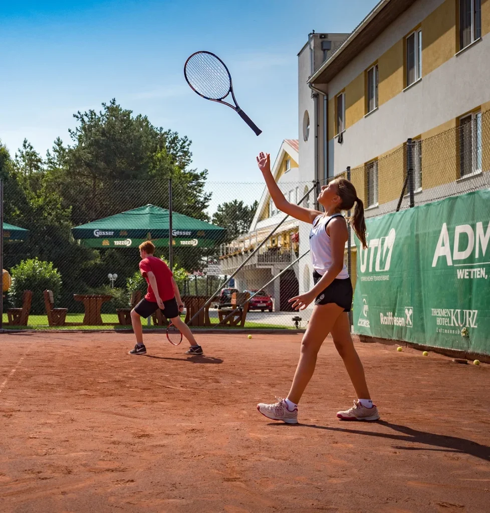 Tennis academy student tossing racket in the air and catching it on court during practice